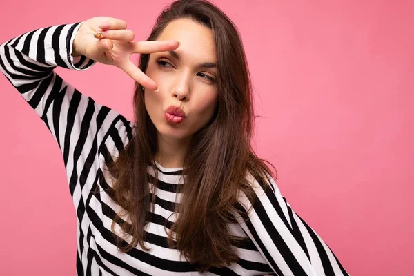 Foto van jonge europese positieve heerlijke gelukkig mooie brunette vrouw met oprechte emoties dragen casual gestreepte pullover geïsoleerd op roze achtergrond met kopieerruimte en het geven van kus — Stockfoto