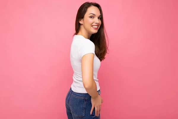 Jonge mooie brunet vrouw. Trendy dame in casual zomer wit t-shirt. Positieve vrouw toont oprechte emoties in het gezicht. Grappig model geïsoleerd op roze achtergrond met vrije ruimte — Stockfoto