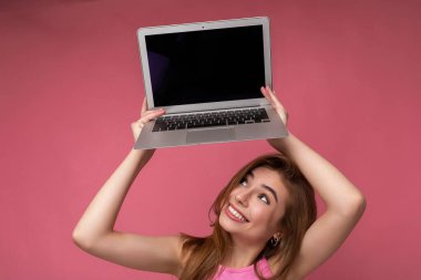 Mutluluktan havalara uçmuş güzel gülümseyen genç bir kadının yan profil portresi elinde bilgisayarla Netbook Montor 'a bakarken duvarın arkasından izole edilmiş şık kıyafetler giyerken eğleniyor.