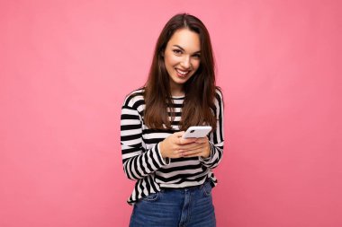 Güzel, genç, esmer bir kadın, duvarda izole edilmiş bir süveter giyip kameraya bakarak mesajlaşarak iletişim kuruyor.