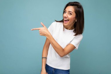 Hoş, hoş, hoş, kazançlı, rahat kıyafetler giyen yetişkin bir kadının fotoğrafı. Arka plan duvarında izole edilmiş ve fotokopi alanı elleriyle boş alanı işaret eden bir fotoğraf.