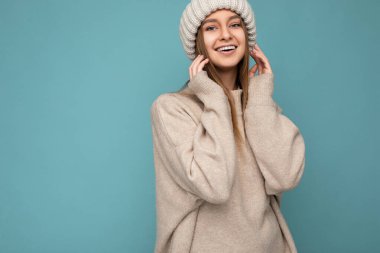 Güzel, pozitif, mutlu, esmer, sarışın bir kadın. Renkli arka plan duvarından izole edilmiş, günlük, şık kıyafetler giymiş. Kameraya bakarken samimi duygular hissediyor.