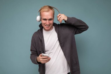 Mavi arka planda izole edilmiş günlük beyaz tişört giyen genç adam.