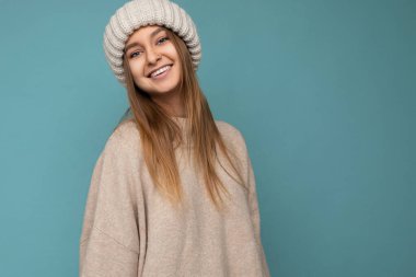 Çekici, gülümseyen, mutlu, esmer, sarışın bir kadın. Renkli arka plan duvarının üzerinde tek başına duruyor. Günlük şık kıyafetler giyiyor ve kameraya bakarak yüz ifadelerini gösteriyor.