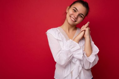 Beyaz bluz giyen, Avrupalı güzel, şık esmer kadın. Kırmızı arka planda, samimi duygularla izole edilmiş. Basit ve doğal bir şekilde kameraya bakıyor. Boş alan