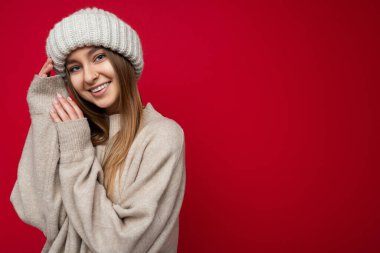 Çekici, sevimli, gülümseyen, mutlu, esmer, sarışın kadın. Renkli arka plan duvarının üzerinde soyutlanmış, günlük şık kıyafetler giymiş, kameraya bakarken yüz ifadelerini gösteriyor.