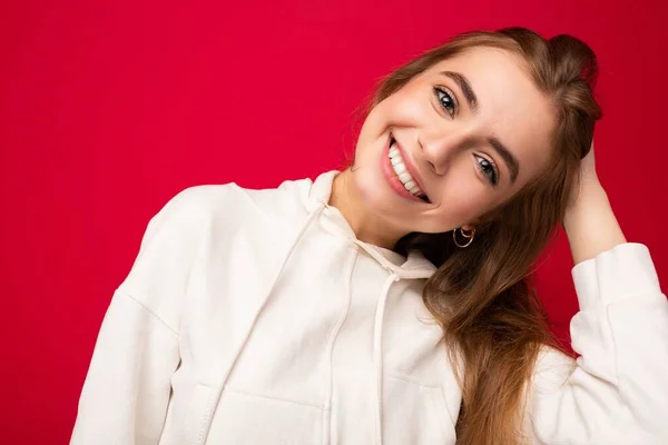 Jonge glimlachende mooie donkerblonde vrouw met oprechte emoties geïsoleerd op de achtergrond muur met kopieerruimte dragen casual witte hoodie. Positief concept — Stockfoto
