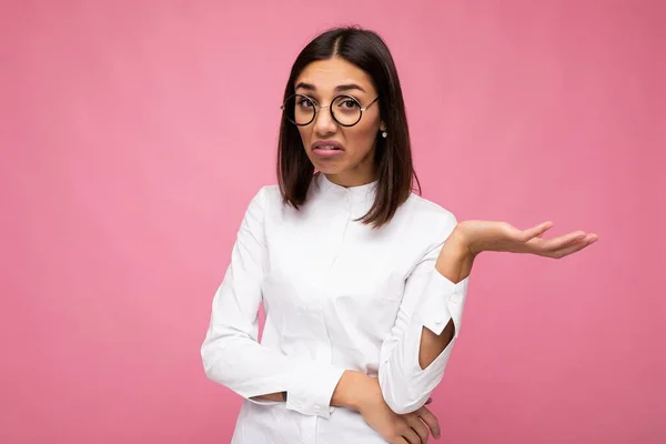 Foto de la hermosa mujer morena joven insatisfecha con ropa casual y gafas ópticas con estilo aislado sobre fondo colorido mirando a la cámara — Foto de Stock