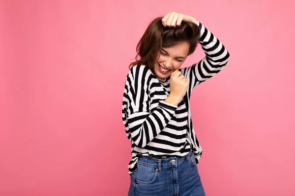 Photo portrait of young beautiful smiling hipster brunette woman in trendy pullover. Sexy carefree female person posing isolated near pink wall with empty space in studio. Positive model with natural — Stock Photo, Image