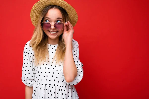 Foto-Foto von schönen positiven Lächeln glücklich fröhlich junge blonde Frau trägt Sommer lässige Kleidung und stilvolle Sonnenbrille isoliert über bunten Hintergrund zur Seite schauen — Stockfoto