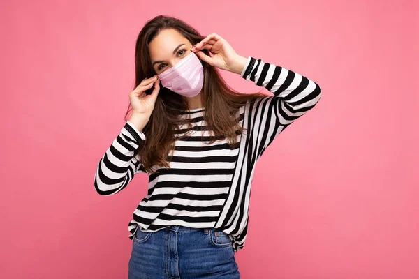 Snímek pozitivní mladé atraktivní ženy se střední obličejovou maskou izolovanou přes zeď na pozadí. Ochrana proti COVID-19 — Stock fotografie