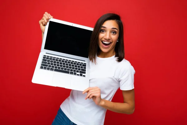 Fotografie a unei femei tinere frumoase care deține laptop-ul computerului uitându-se la camera izolată pe fundal colorat — Fotografie, imagine de stoc