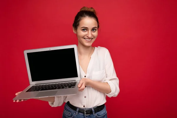 Φωτογραφία της όμορφης νεαρής γυναίκας που κρατά φορητό υπολογιστή κοιτάζοντας την κάμερα απομονωμένη σε πολύχρωμο φόντο — Φωτογραφία Αρχείου