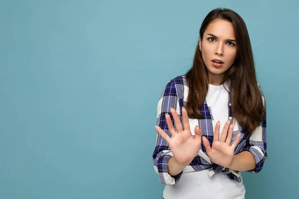 Joven mujer morena hermosa insatisfecha seria con emociones sinceras usando camisa de chequeo de moda de pie aislado sobre fondo azul con espacio vacío y mostrando gesto de stop diciendo que no. Negativo. — Foto de Stock