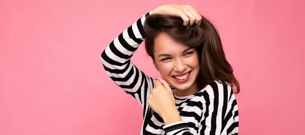 Panoramisch fotoportret van jonge mooie glimlachende hippe brunette vrouw in trendy trui. Sexy zorgeloze vrouwelijke persoon poseren geïsoleerd in de buurt van roze muur met lege ruimte in de studio. Positief model — Stockfoto