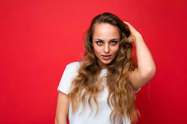 Jovem bela mulher loira encaracolado com expressão sexy, rosto alegre e feliz vestindo casual t-shirt branca isolada sobre fundo vermelho com espaço de cópia — Fotografia de Stock