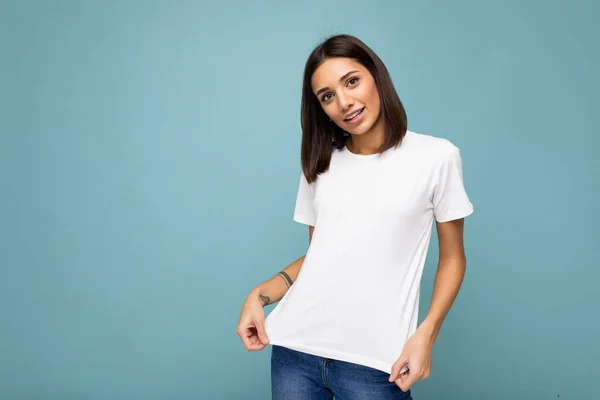 Ritratto di giovane donna bruna allegra e allegra positiva sorridente in t-shirt bianca casual per mockup isolato su sfondo blu con spazio copia — Foto Stock