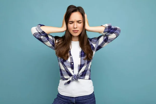 Nechci o tom slyšet. Mladá emocionální krásná bruneta žena nosí kostkovanou košili izolované na modrém pozadí s kopírovacím prostorem a zakrývající uši — Stock fotografie
