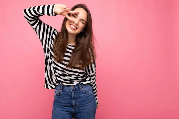 Photo of young european positive smiling winsome happy beautiful brunette woman with sincere emotions wearing casual striped pullover isolated on pink background with copy space — Stock Photo, Image