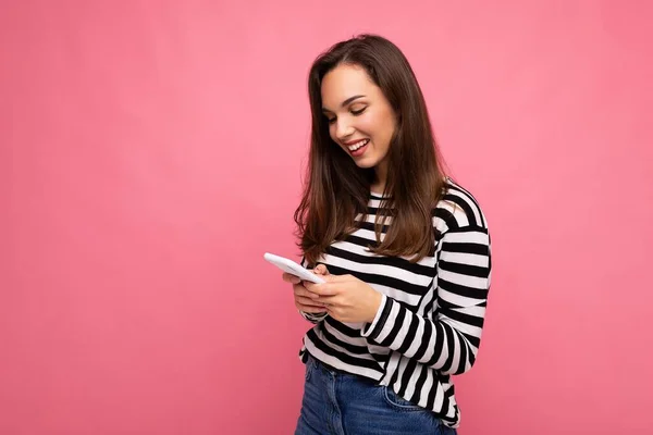 웃고 있는 예쁜 젊은 갈색 머리 여자가 핸드폰 통화를 하며 문자 메시지를 보내는 사진. — 스톡 사진
