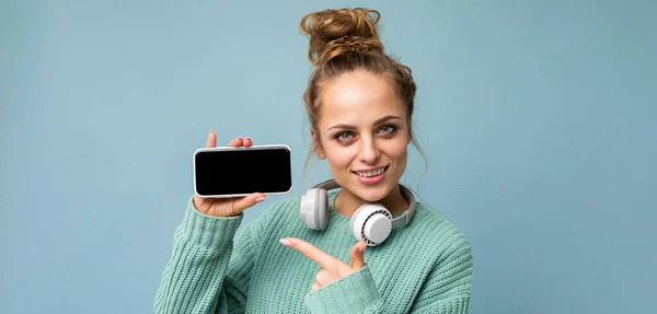 Panoramic closeup photo of Attractive positive smiling young woman wearing stylish casual outfit isolated on colourful background wall holding and showing mobile phone with empty screen for cutout — Stock Photo, Image