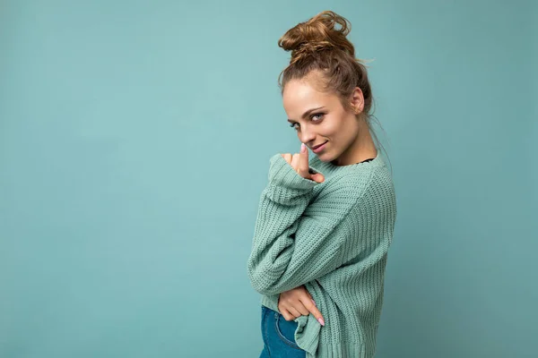 Young beautiful cute curly blonde woman with sexy expression, cheerful and happy face wearing trendy blue sweater isolated over blue background with copy space — Stock Photo, Image