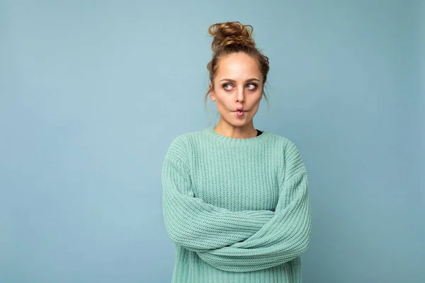 Tiro de joven divertida alegre mujer rubia bonita alegre con jersey azul aislado sobre fondo azul con espacio vacío y divertirse. Concepto positivo — Foto de Stock