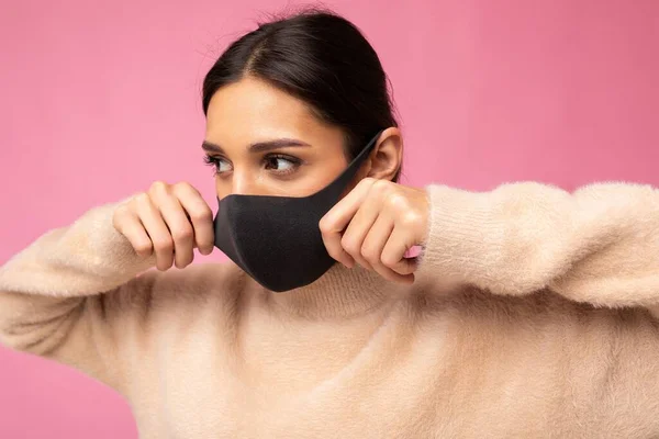 Mladá krásná žena v opakovaně použitelný virus ochranné masky na tváři proti koronaviru izolované na růžové pozadí zdi — Stock fotografie