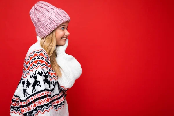 Side-profile photo of pretty smiling happy young blonde woman standing isolated over colourful background wall wearing everyday trendy clothes looking to the side