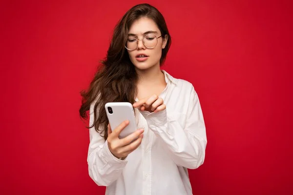 아름다운 젊은 여성 이 평상복을 입고 인터넷에서 온라인 서핑을 하며 고립된 채 핸드폰을 통해 모바일 스크린을 보고 있습니다. — 스톡 사진