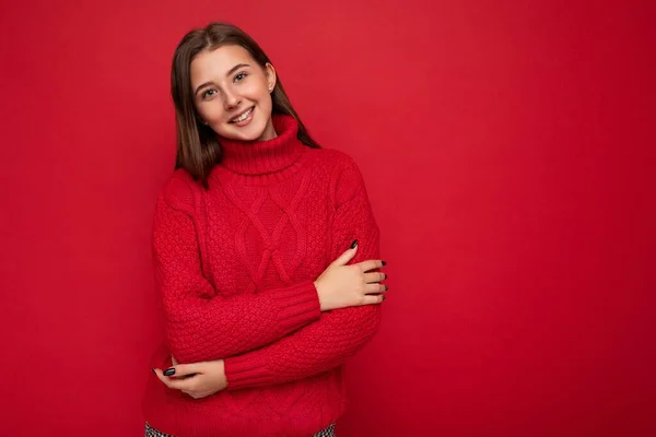 Jonge glimlachende mooie brunette vrouw met oprechte emoties geïsoleerd op de achtergrond muur met kopieerruimte dragen casual rode trui. Positief concept — Stockfoto