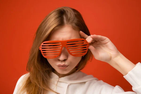 Foto de una hermosa mujer rubia positiva que usa ropa casual y gafas ópticas elegantes aisladas sobre una colorida pared de fondo mirando a la cámara —  Fotos de Stock