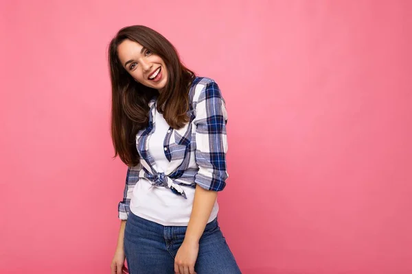 Portrait photo de jeune belle femme brune hipster souriante en chemise et jeans bleu et blanc tendance. Sexy insouciante femme posant isolé près du mur rose avec espace vide en studio — Photo