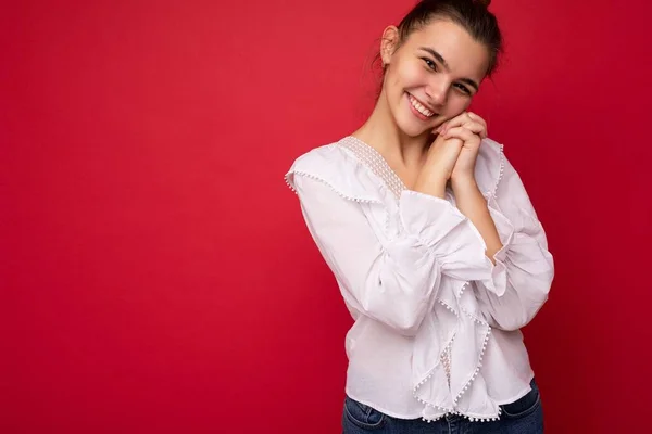 Молодая красивая европейская стильная брюнетка в белой блузке на красном фоне с положительными искренними эмоциями. Простой и естественный взгляд на камеру. Свободное пространство — стоковое фото