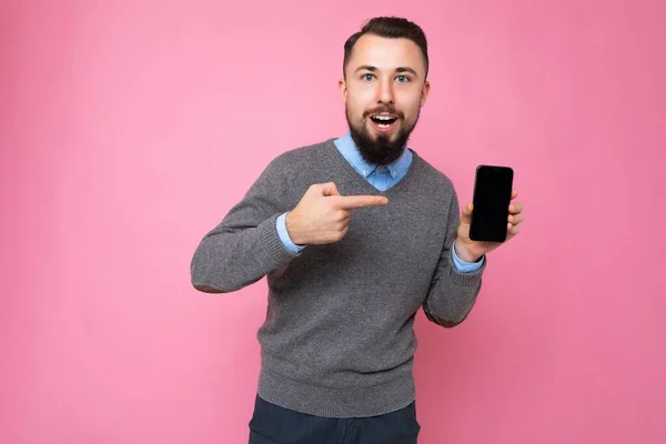 Handsome happy cool young man good looking wearing casual stylish clothes standing isolated over colourful background wall holding smartphone and showing phone with empty screen display looking at — Stock Photo, Image