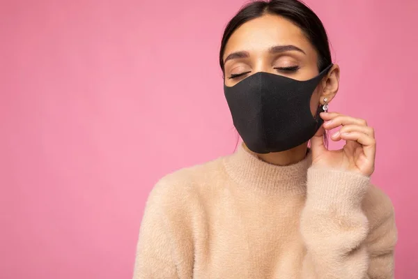 Mladá krásná žena v opakovaně použitelný virus ochranné masky na tváři proti koronaviru izolované na růžové pozadí zdi — Stock fotografie