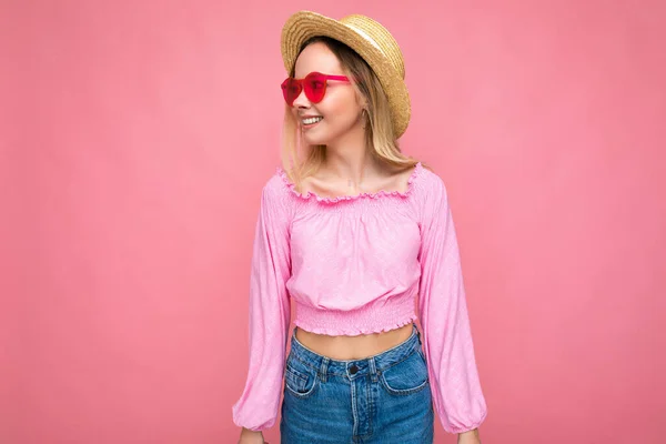 Foto tiro de atraente feliz sorrindo jovem loira vestindo roupas casuais de verão e óculos de sol elegantes isolados sobre parede de fundo colorido olhando para o lado — Fotografia de Stock
