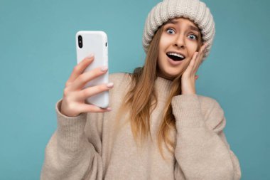 Çekiciliğin fotoğrafı şaşkına dönmüş, şık giyinen, arka planda izole edilmiş, el ele tutuşmuş ve cep telefonu mesajları kullanan hoş görünümlü genç bir kadını hayrete düşürdü.