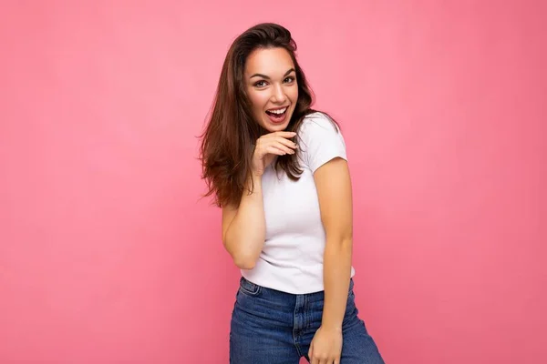 Foto retrato de la joven hermosa mujer morena hipster sonriente en camiseta blanca con maqueta. Sexy persona femenina despreocupada posando aislada cerca de la pared rosa con espacio vacío en el estudio. Modelo positivo —  Fotos de Stock