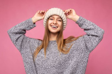 Çekici, gülümseyen, mutlu, esmer, sarışın bir kadın. Renkli arka plan duvarının üzerinde izole bir şekilde duruyor. Günlük şık kıyafetler giyiyor ve kameraya bakarken yüz ifadelerini gösteriyor.