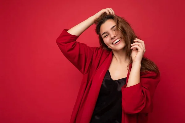 Портрет молодой привлекательной кавказской хипстерши в модной повседневной одежде. Сексуальная беззаботная женщина позирует в студии рядом с красной стеной. Пустое пространство — стоковое фото