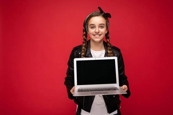 Фото красивой молодой девушки, держащей ноутбук, смотрящей в камеру на цветном фоне — стоковое фото