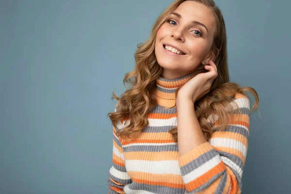 Retrato de jovem winsome atraente feliz sorrindo mulher loira com cabelo ondulado vestindo camisola listrada isolado sobre fundo azul com espaço vazio — Fotografia de Stock