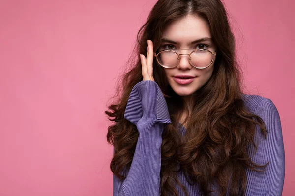 Photo shot of beautiful positive young brunette woman wearing casual clothes and stylish optical glasses isolated over colorful background wall looking at camera — Stock Photo, Image