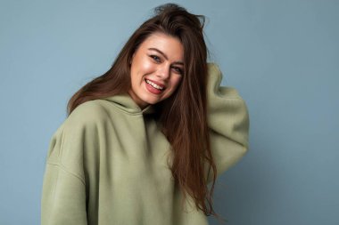 Yeni moda haki kapüşonlu güzel, beyaz, gülümseyen kadın modelin portresi. Mavi arka planda, fotokopi alanı ile izole edilmiş. Pozitif kavram