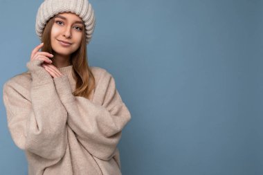 Çekici, gülümseyen, mutlu, esmer, sarışın bir kadın. Renkli arka plan duvarının üzerinde tek başına duruyor. Günlük şık kıyafetler giyiyor ve kameraya bakarak yüz ifadelerini gösteriyor.