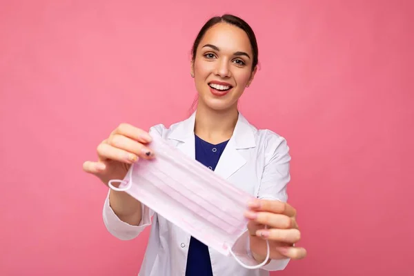 Glad kaukasiska kvinna visar skydd ansikte mask isolerad på rosa bakgrund. Coronavirus eller Covid-19-koncept — Stockfoto