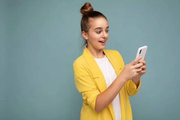 Hermosa adolescente joven con ropa casual de pie aislado sobre fondo navegar por Internet a través del teléfono mirando a la pantalla móvil — Foto de Stock