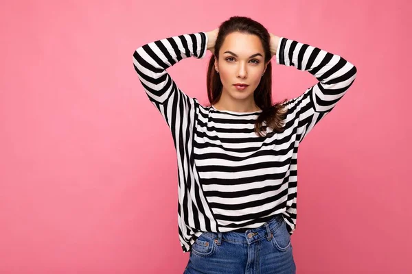 Fotografie mladé sebevědomí vážné krásné brunetky žena s upřímnými emocemi na sobě ležérní pruhované svetr izolované na růžovém pozadí s kopírovacím prostorem — Stock fotografie