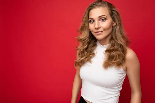 Photo portrait of young sexy beautiful attractive positive smiling blonde woman wearing white top isolated over red background with copy space — Stock Photo, Image